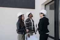 A diverse group of professionals in construction helmets reviewing property plans outdoors.